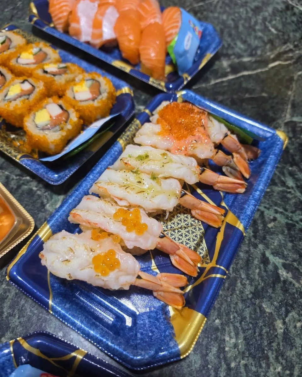 Prawn nigiri with assorted toppings in a blue tray