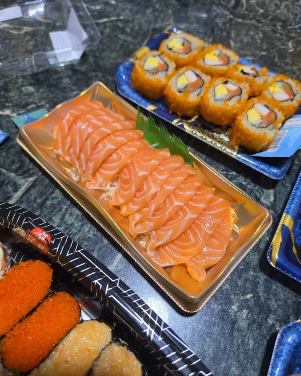 Salmon sashimi arranged in a gold takeaway tray