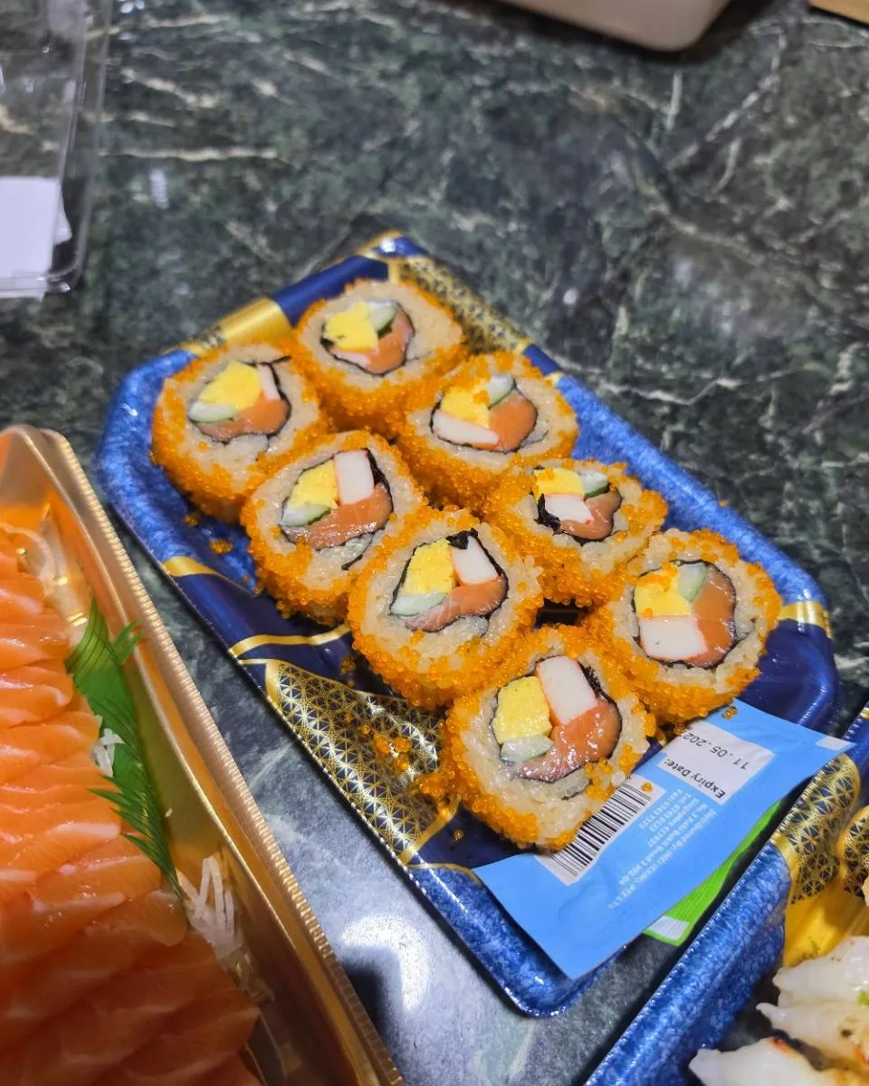 Maki coated with orange roe, showing salmon, cucumber, egg and crabstick fillings